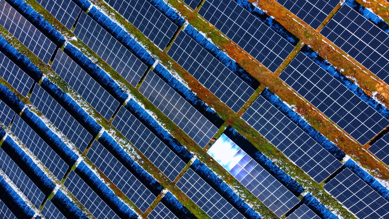 Trama aerea astratta di un impianto di pannelli solari blu. Inquadratura dall'alto di file ripetute di moduli fotovoltaici su una superficie erbosa. Tecnologia per l'energia pulita.