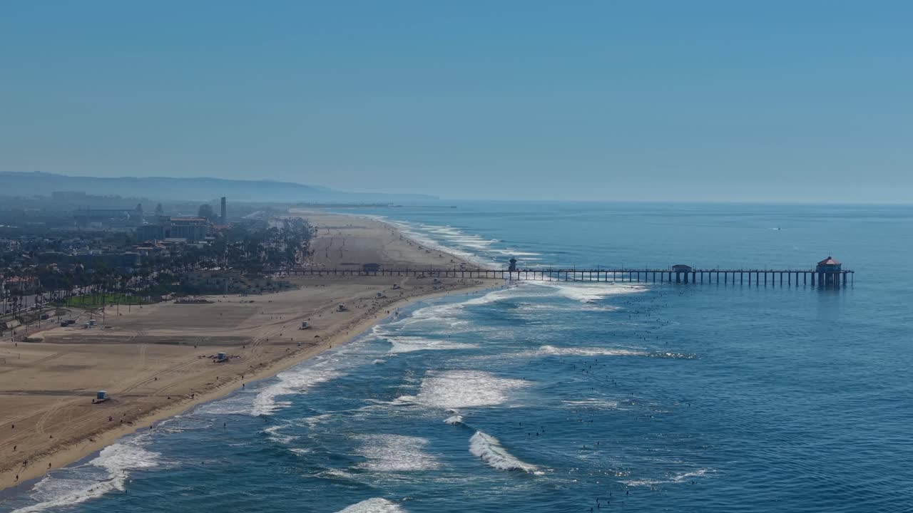 Coastal view of Huntington Beach Pier, Orange County California, wide aerial Landscape looking south toward Newport and Laguna. Pacific West Coast, surfing waves, sandy beaches, sunny summer day