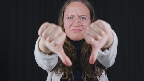 attractive curly haired woman shakes head pointing thumbs down vigorously disagreeing disapproving