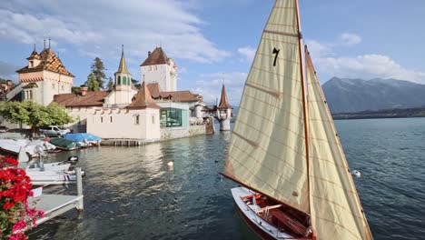 old church on the edge of the beautiful blue lake with a classic sail boat and flowers in switzerland