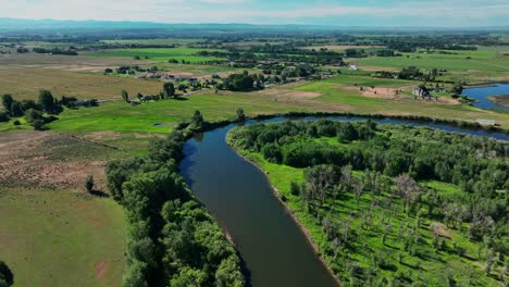 Vista-Panorámica-Del-Río-Y-Los-Campos-Verdes-En-Saint-Anthony,-Idaho---Toma-Aérea-De-Drones