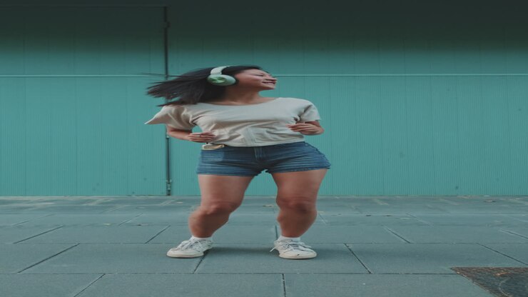 Woman dancing with headphones outdoors