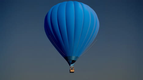 blue hot air balloon against a dark sky