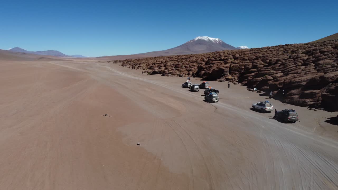 볼리비아의 알티플라노 사막에서 침식된 바위 절벽에 의해 관광 트럭이 멈다.