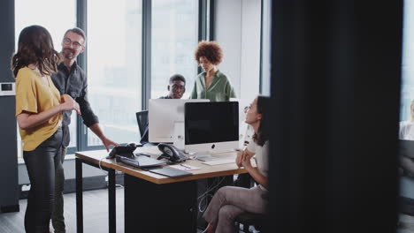 Creative-business-team-working-together-and-talking-in-a-busy-casual-office,-seen-from-doorway