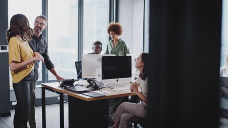 creative business team working together and talking in a busy casual office, seen from doorway
