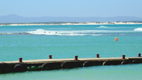 Scenic-and-pristine-blue-water-and-jetty-along-Struisbaai-coastline,-Overberg