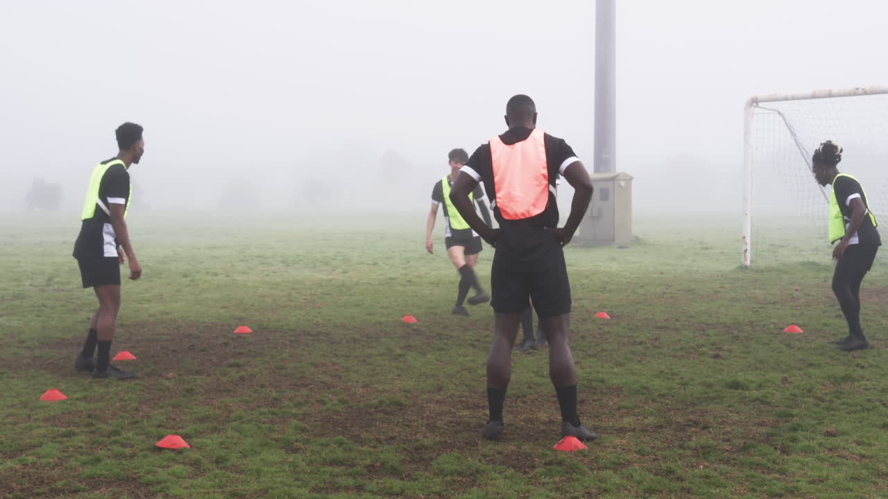 Soccer players practicing on foggy field, focusing on teamwork and skills