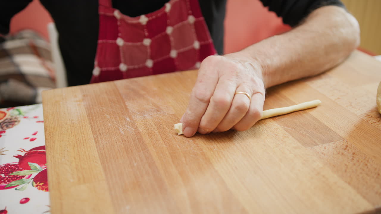 Mans Hands Rolling and Splitting Raw Dough For Italian Pasta