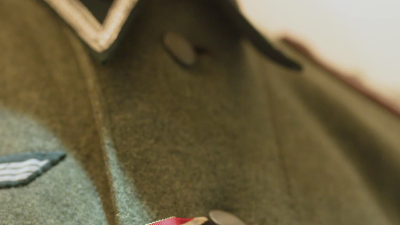 Detailed close-up pan of historical German military uniform and medal ribbon under soft lighting