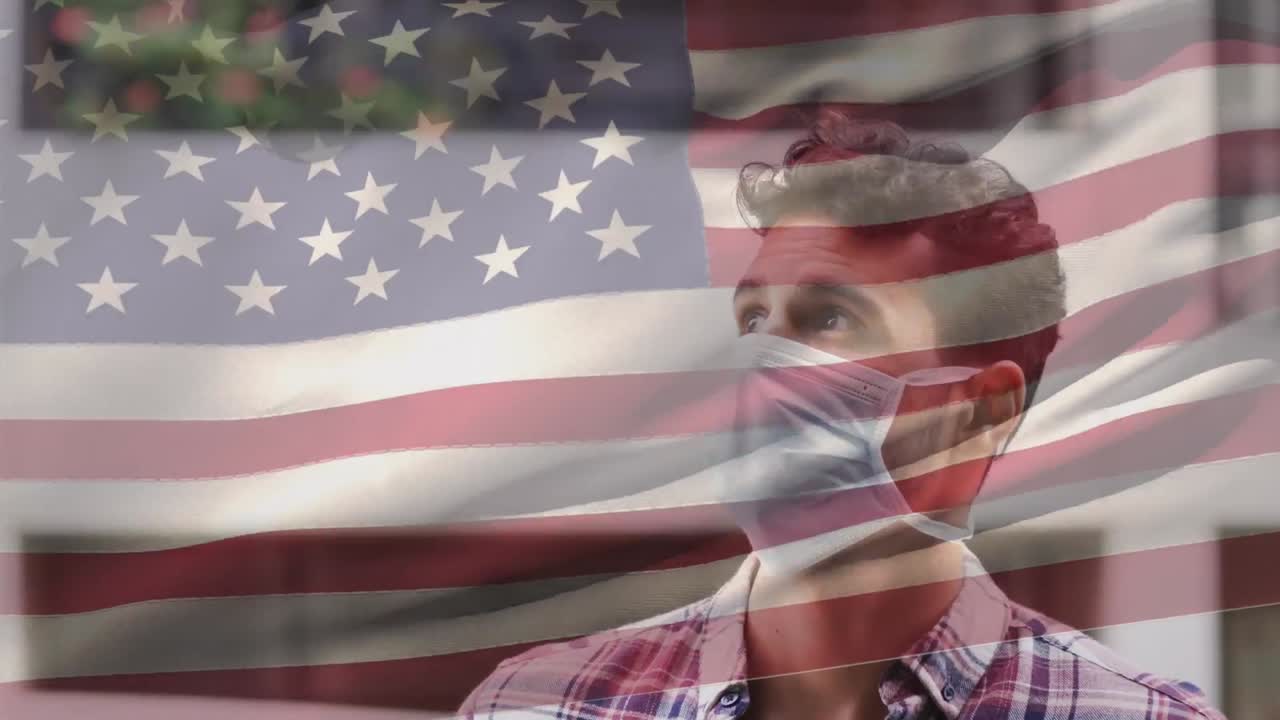 bandera estadounidense ondeando contra el retrato de un hombre caucásico con máscara facial en la calle
