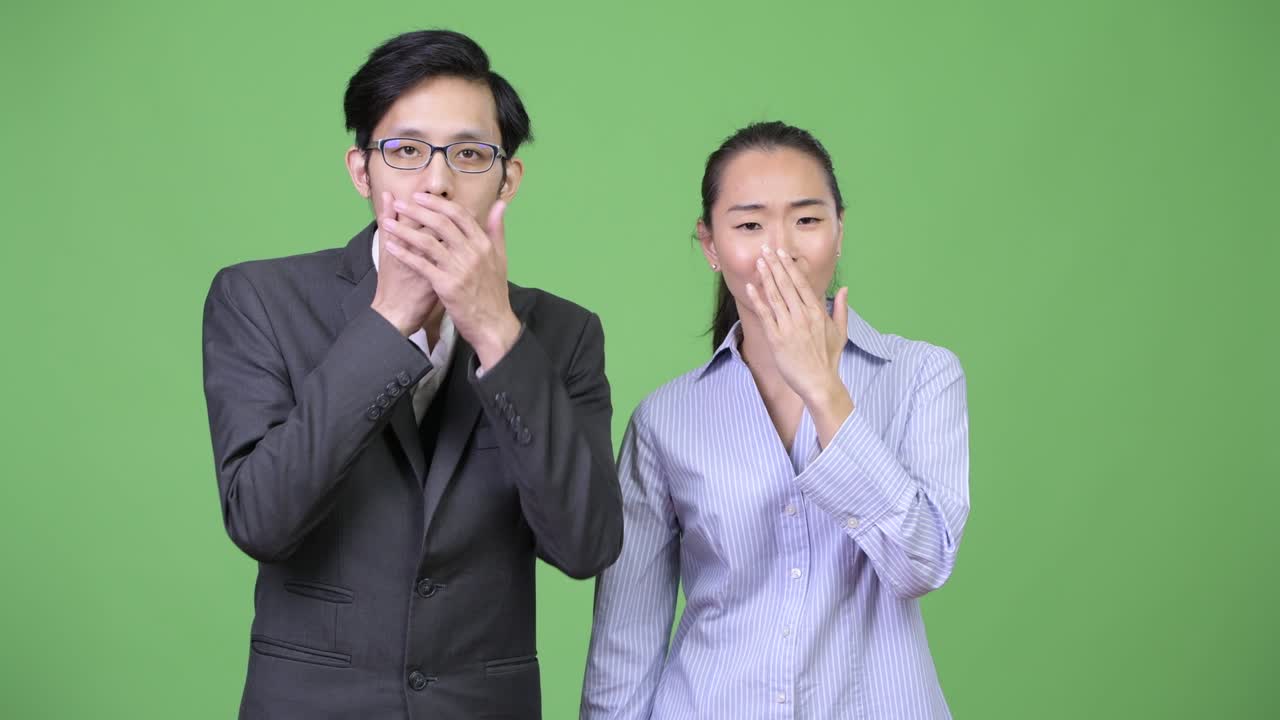 Young Asian business couple looking shocked together