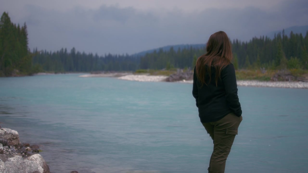 Woman standing at the river and looking at the scenic landscape