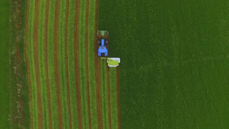 vista aérea de un tractor cortando la hierba en un gran campo verde