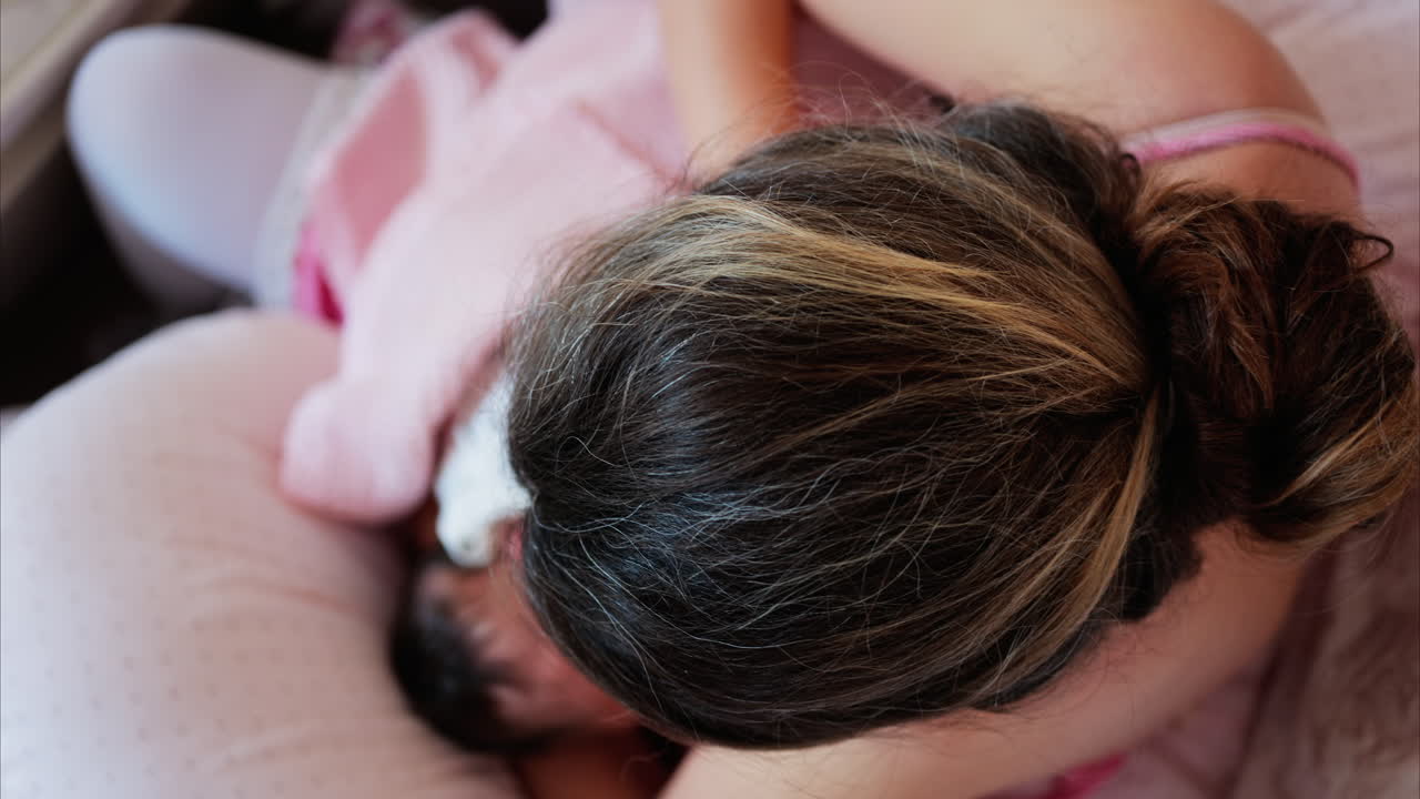 Overhead shot of a mother breastfeeding her newborn baby in a quiet, nurturing environment