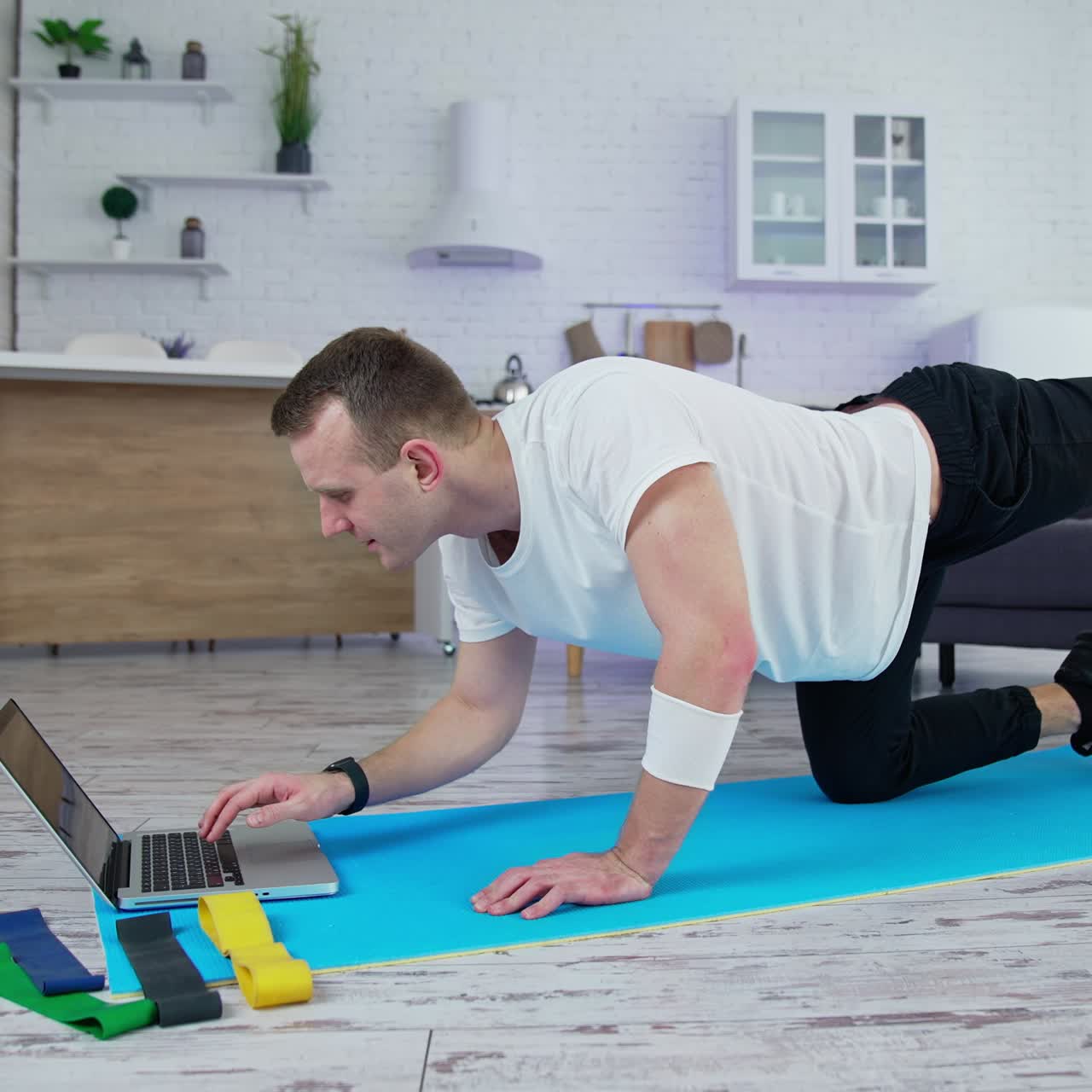 Young lifestyle sportsman working out in front of his laptop computer at home. Training body indoor by strong handsome man. Full length