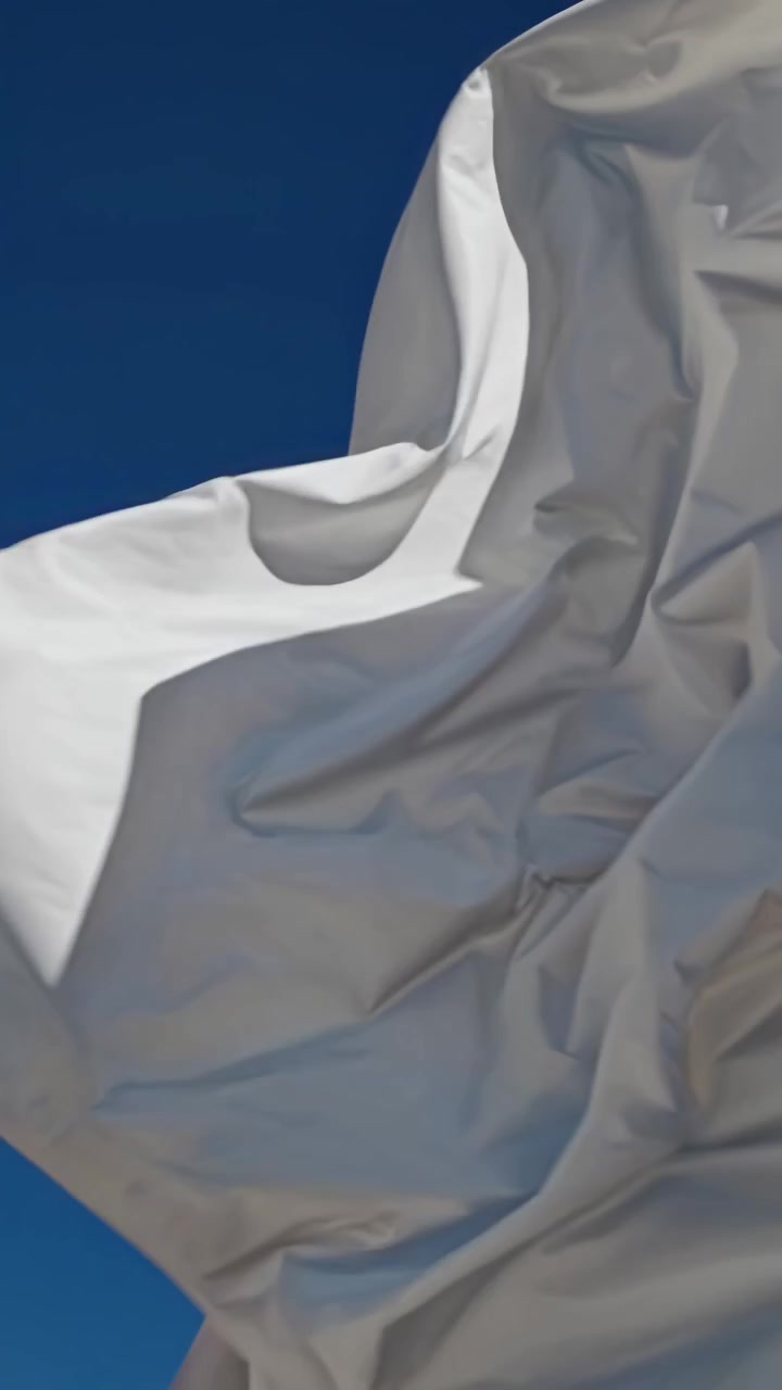 Tessuto bianco astratto che fluttua contro un cielo azzurro limpido
