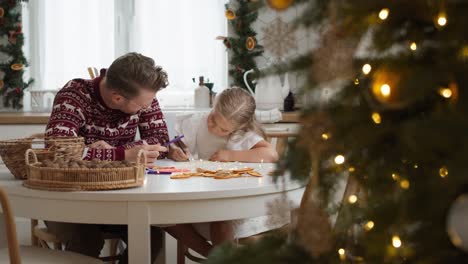 escribiendo una carta a papá noel por una niña linda con su papá