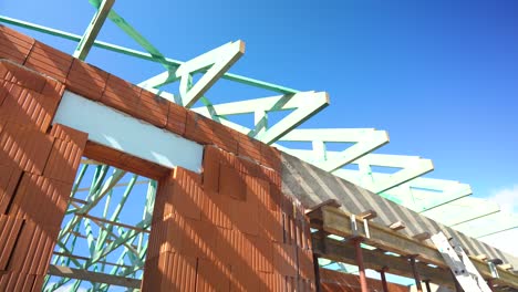 timber roof truss installation over brick structure during construction on bright sunny day