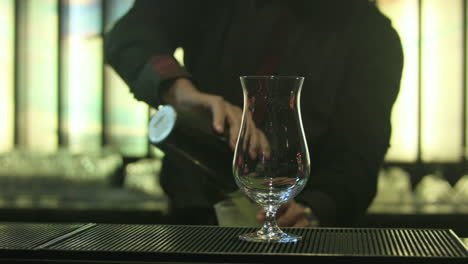 bartender pouring a cold margarita with ice in a glass