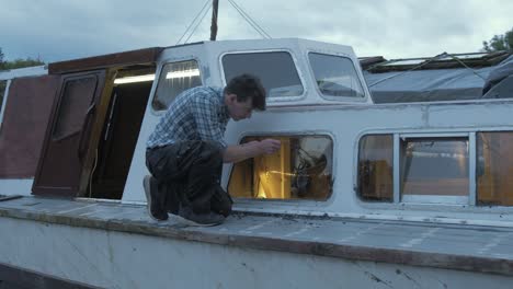 Carpenter-scraping-removing-window-seal-on-wooden-liveaboard