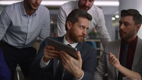 un grupo de compañeros de trabajo multirraciales investigando datos corporativos usando tablets en la oficina.