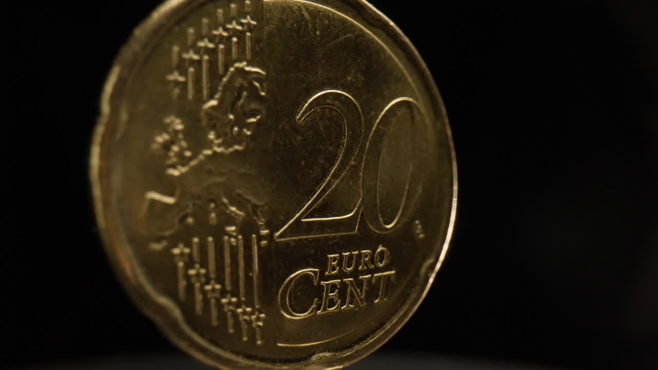 primer plano de una moneda de 20 céntimos de euro con un fondo negro que está girando