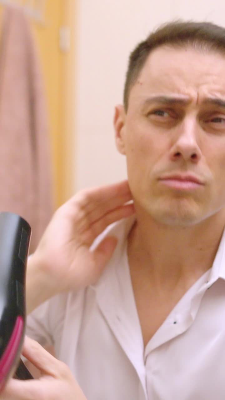 Handsome man drying hair in bathroom mirror