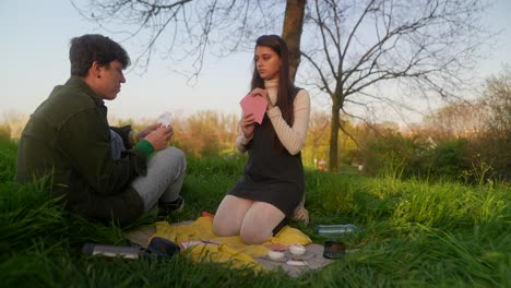 young couple playing cards in a park at sunset