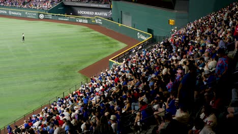 slow motion landscape of fans supporters and crowd watching baseball game match from stands with players on field at stadium in arlington texas usa america