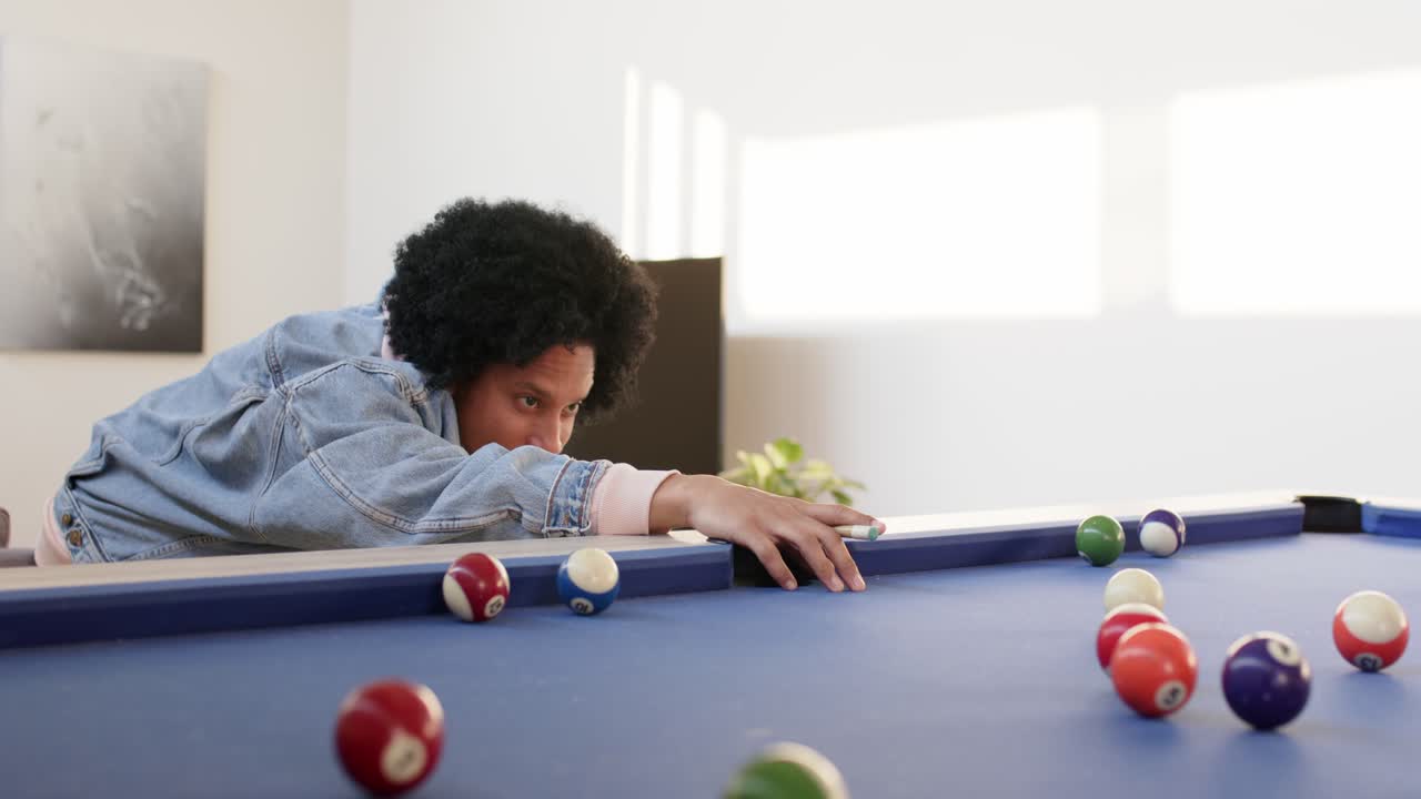 Entering frame mid-adult man holding cue stick on rec room table, striking cue ball, copy space