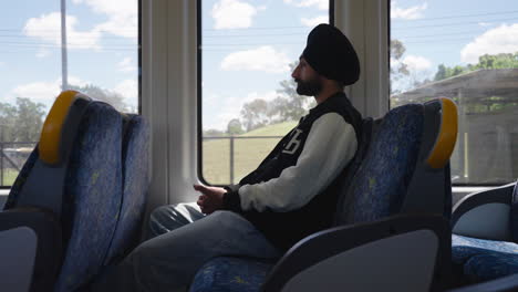 an indian traveler punjabi sikh man sitting in a moving train