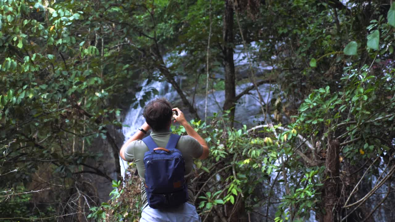 viajar joven caminando por la cascada y tomar fotos y videos en el teléfono