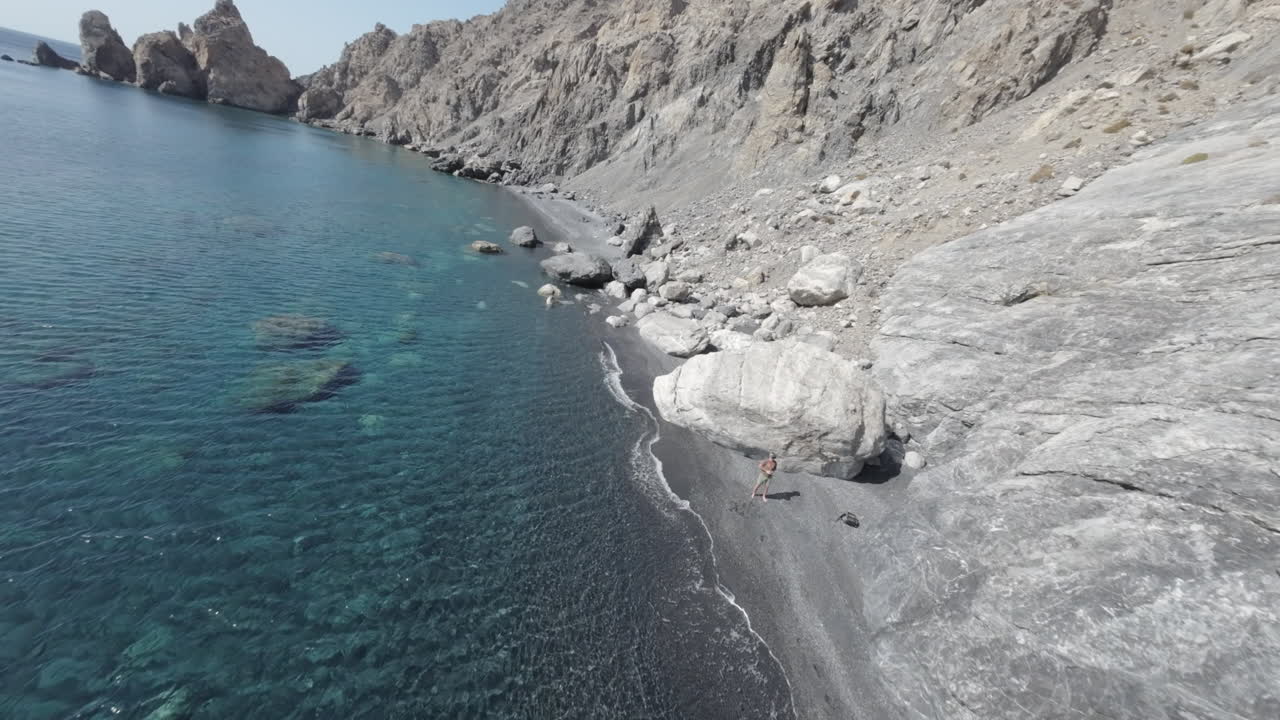 First Person View of a drone diving over turquoise water and stunning rock formations of Aspes Black Beach, South Crete, Greece