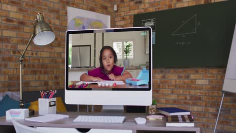 Webcam-view-of-african-american-boy-on-video-call-on-computer-on-table-at-school