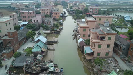 aerial shot of an asian village located along polluted river with moored boats