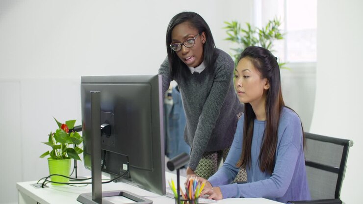 Two Young Business Women Working at Computer