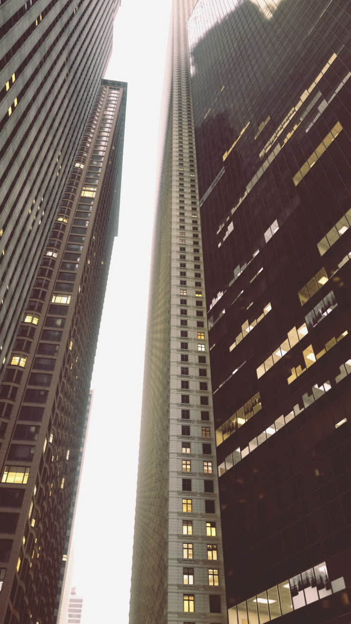 Urban canyon formed by tall buildings under cloudy sky at dusk