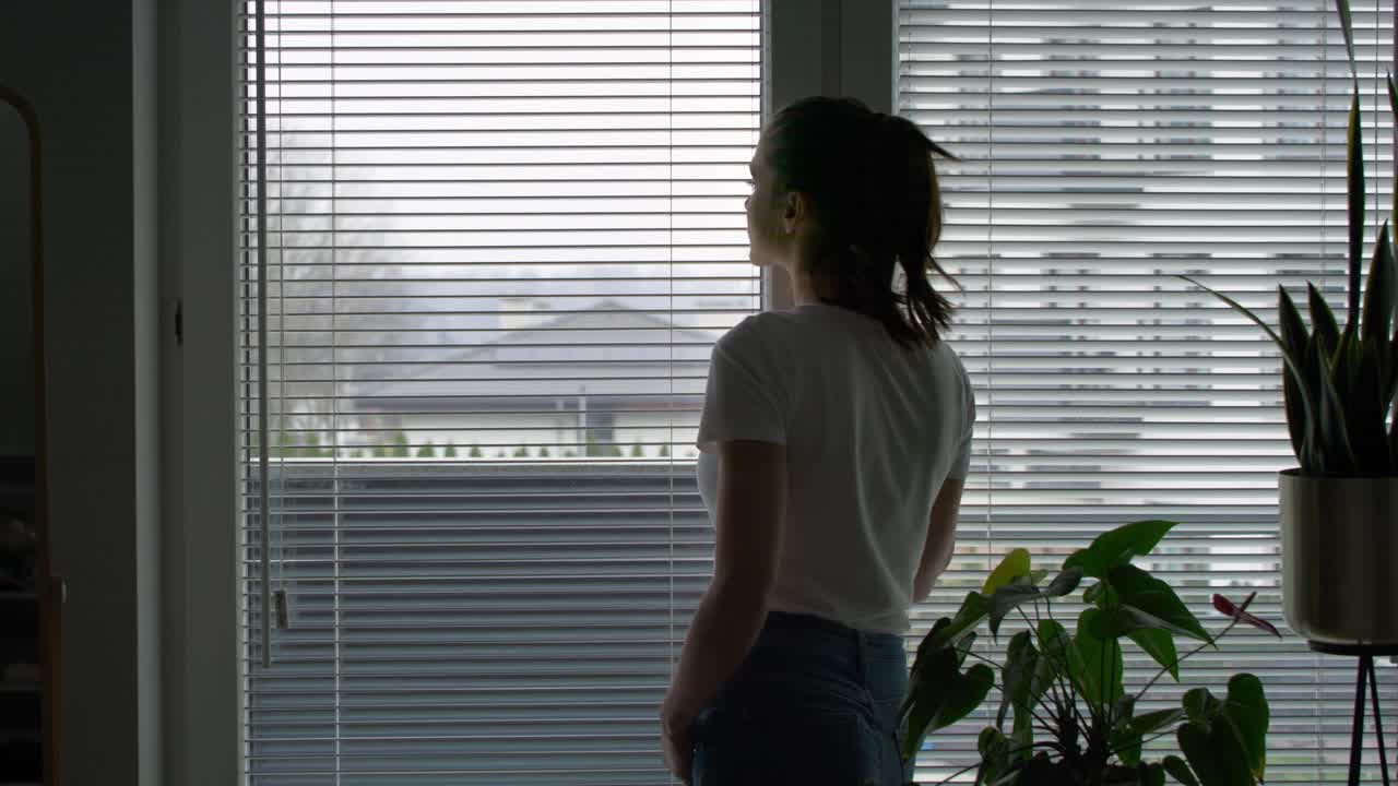 Vista de espalda de mujer mirando por la ventana