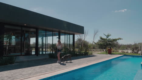 young woman walking her dog at a pet friendly modern resort, slow motion