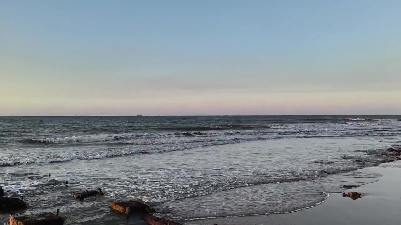 Onde leggere che si infrangono su una spiaggia rocciosa al tramonto