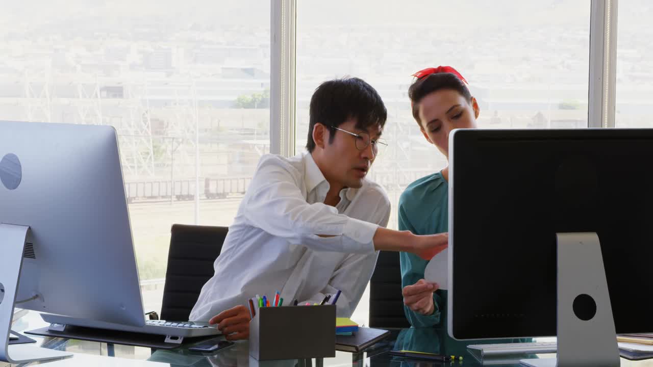 Front view of Mixed-race Business people discussing over computer at desk in office 4k