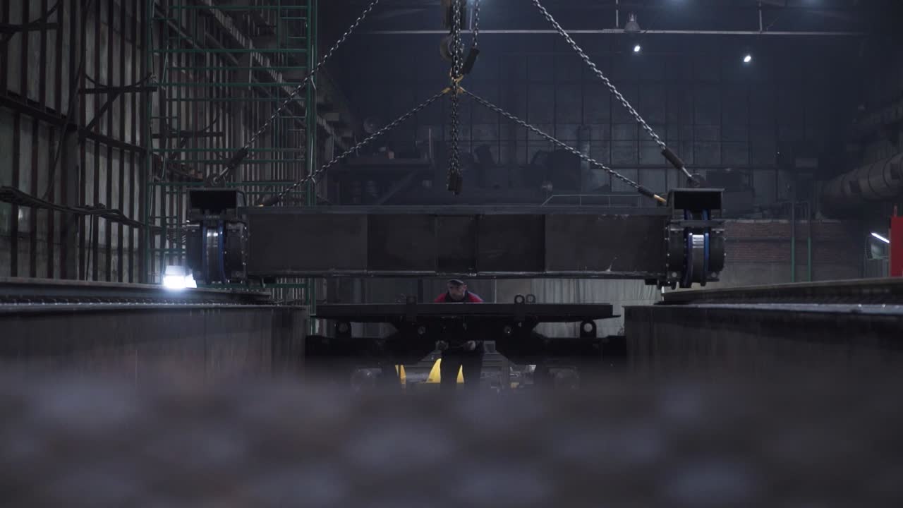 Industrial Worker Lifting Heavy Metal Parts in a Factory