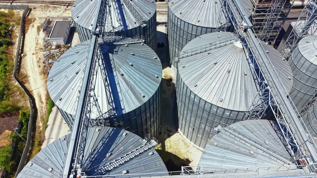 Grain silos located at an agricultural facility with rail tracks nearby during clear weather