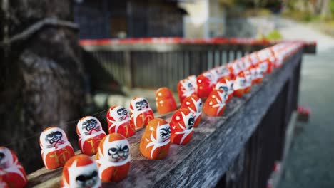 daruma good luck dolls on fence in line at katsuo-ji temple in minoh osaka