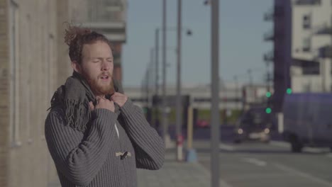 man wearing scarf standing on the street breathing deeply