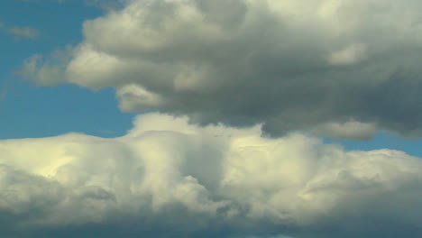 Billowy-white-clouds-with-gray-undertones-pass-against-a-blue-sky