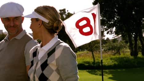 Golfing-couple-smiling-at-the-eighteenth-hole-on-the-golf-course