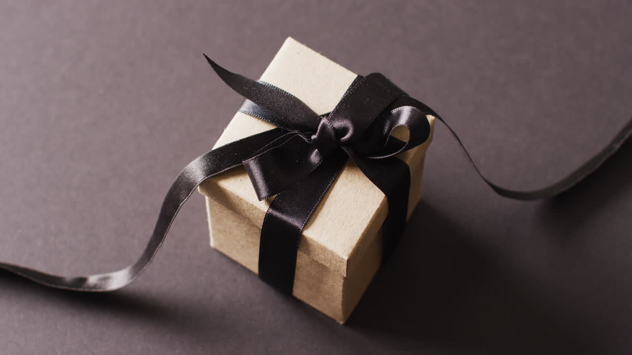 복사 공간과 함께 어두운 회색 배경에 검은 리본으로 인 선물 상자의 비디오