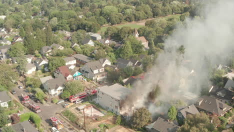 aerial shot towards fire engines surrounding a burning building